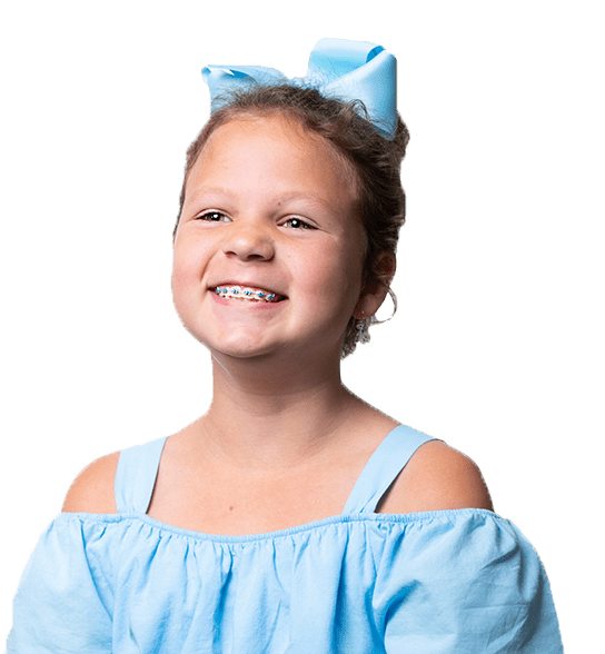 Young girl smiling with blue bow in hair, blue metal braces, off-the-shoulder blue shirt