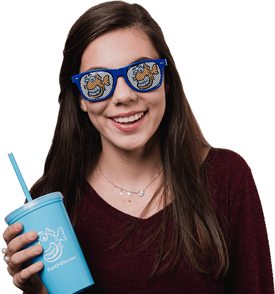 young girl smiling, straight white teeth, fishbein orthodontics logo on blue sunglasses, holding blue cup with fishbein othodontics logo
